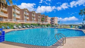 A swimming pool with lounge chairs and a building with balconies.