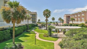 A resort with multiple-story buildings, a well-maintained lawn, and a clear view of the ocean.