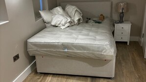 Un dormitori amb llit, tauleta de nit i làmpada.