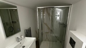 Un bany modern amb un rentaplat, un vàter i una dutxa amb envàs de vidre.