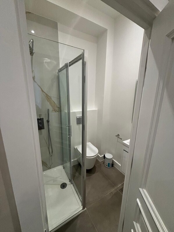 Un baño moderno con ducha envuelta en vidrio, inodoro y lavamanos.
