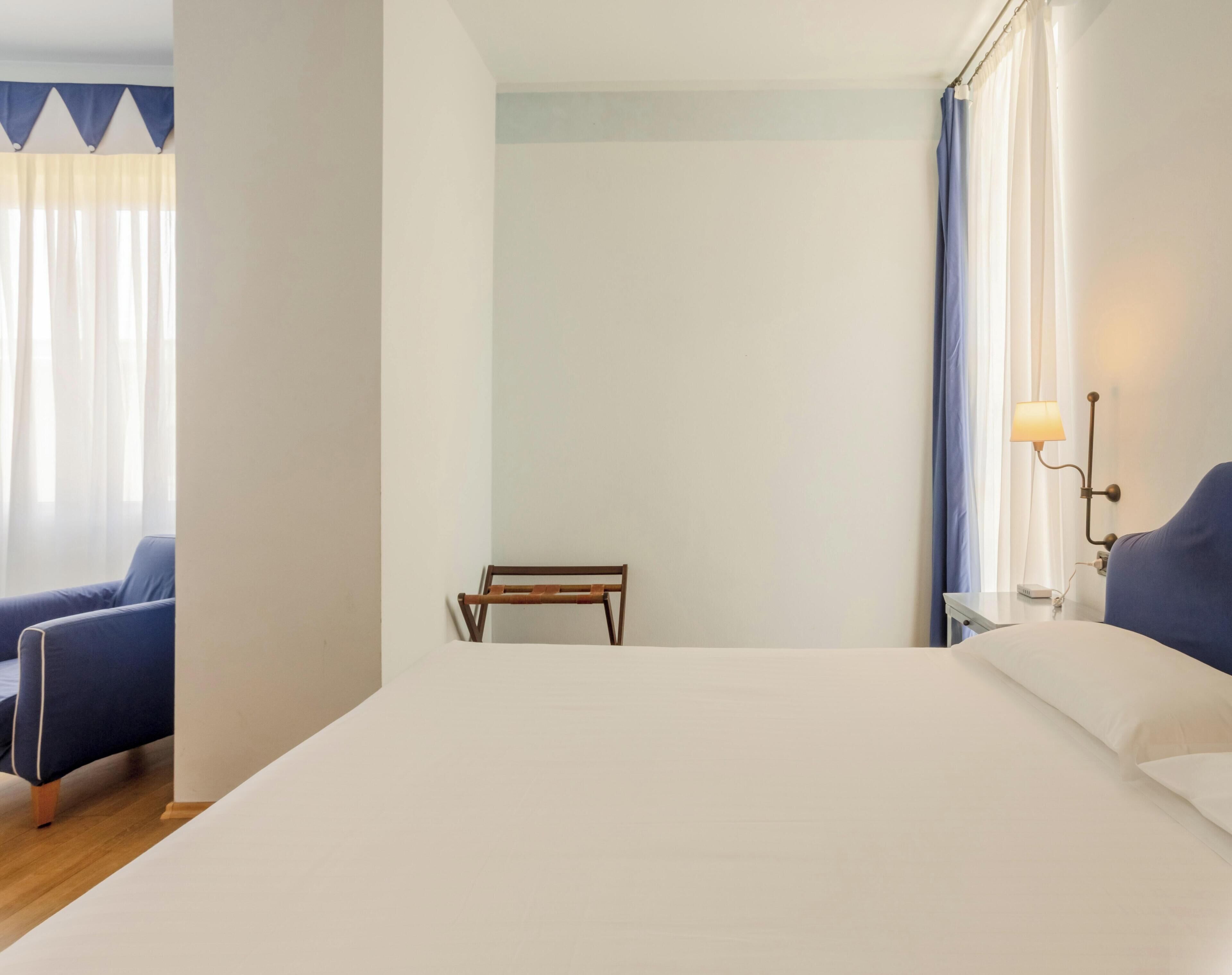Ein Hotelzimmer mit einem Bett, einem Sessel, einem kleinen Tisch und einer Lampe.