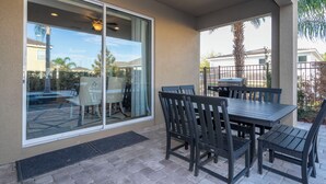 An outdoor patio with a table and chairs, a grill, and a view of the neighborhood. - Classic 8bd house - Encore Reunion Close to Disney (Kissimmee)