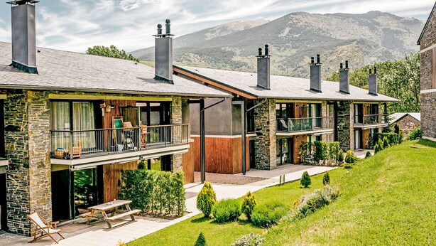 A modern multi-story building with stone facades, balconies, and chimneys. - Apartment Ferreries with heated swimming pool, garden, WiFi, equipped kitchen (Saillagouse)