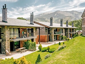 Un moderno edificio de varios pisos con fachadas de piedra, balcones y chimeneas.