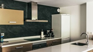 A modern kitchen with a dark backsplash, stainless steel appliances, and a white refrigerator. - Apartment Ferreries with heated swimming pool, garden, WiFi, equipped kitchen (Saillagouse)