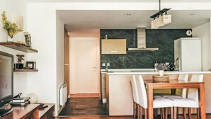 A modern kitchen with a dark backsplash, wooden cabinets, and a built-in island with seating. - Apartment Ferreries with heated swimming pool, garden, WiFi, equipped kitchen (Saillagouse)