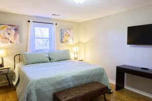A bedroom with a bed, bedside lamps, a TV, and artwork on the walls. - The Bluegrass Railway Inn (Midway)
