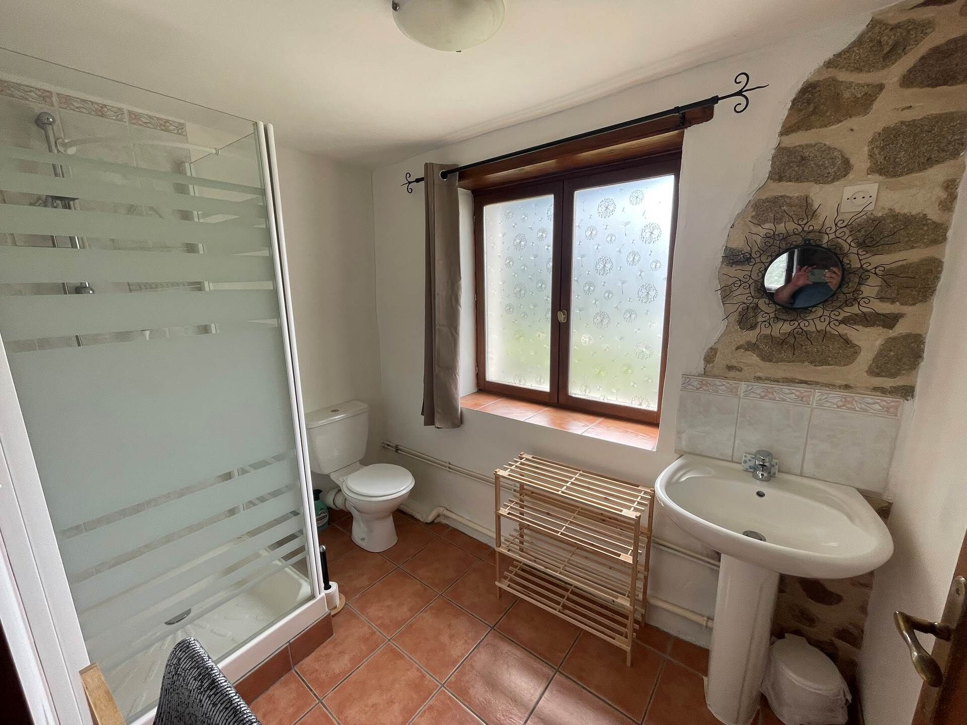 Une salle de bain avec une douche à parois de verre, des toilettes, une fenêtre à verre dépoli, un lavabo et un porte-serviettes.