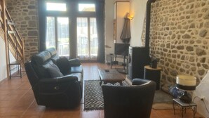 Uma sala de estar com parede de pedra, lareira, sofá e televisão.