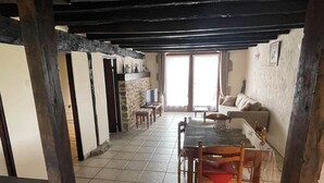 A dining area with a table and chairs, a stone wall, and a view of the outside through a window.