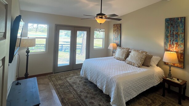 A bedroom with a large bed, two bedside lamps, a ceiling fan, and a rug. - 3-Br Nature Oasis in rolling hills of Burton, 15 minutes from Round Top (Burton)
