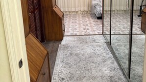 Une pièce avec une armoire en bois, un tapis à motifs, une cloison en verre et un vélo à l’arrière-plan.