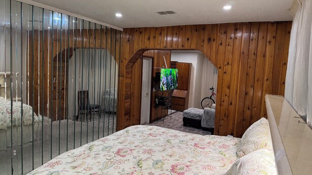 Une chambre à coucher avec un lit, une armoire, un vélo et un miroir.