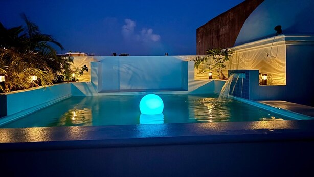 A pool with a glowing orb, a waterfall, and a modern building with a dome.