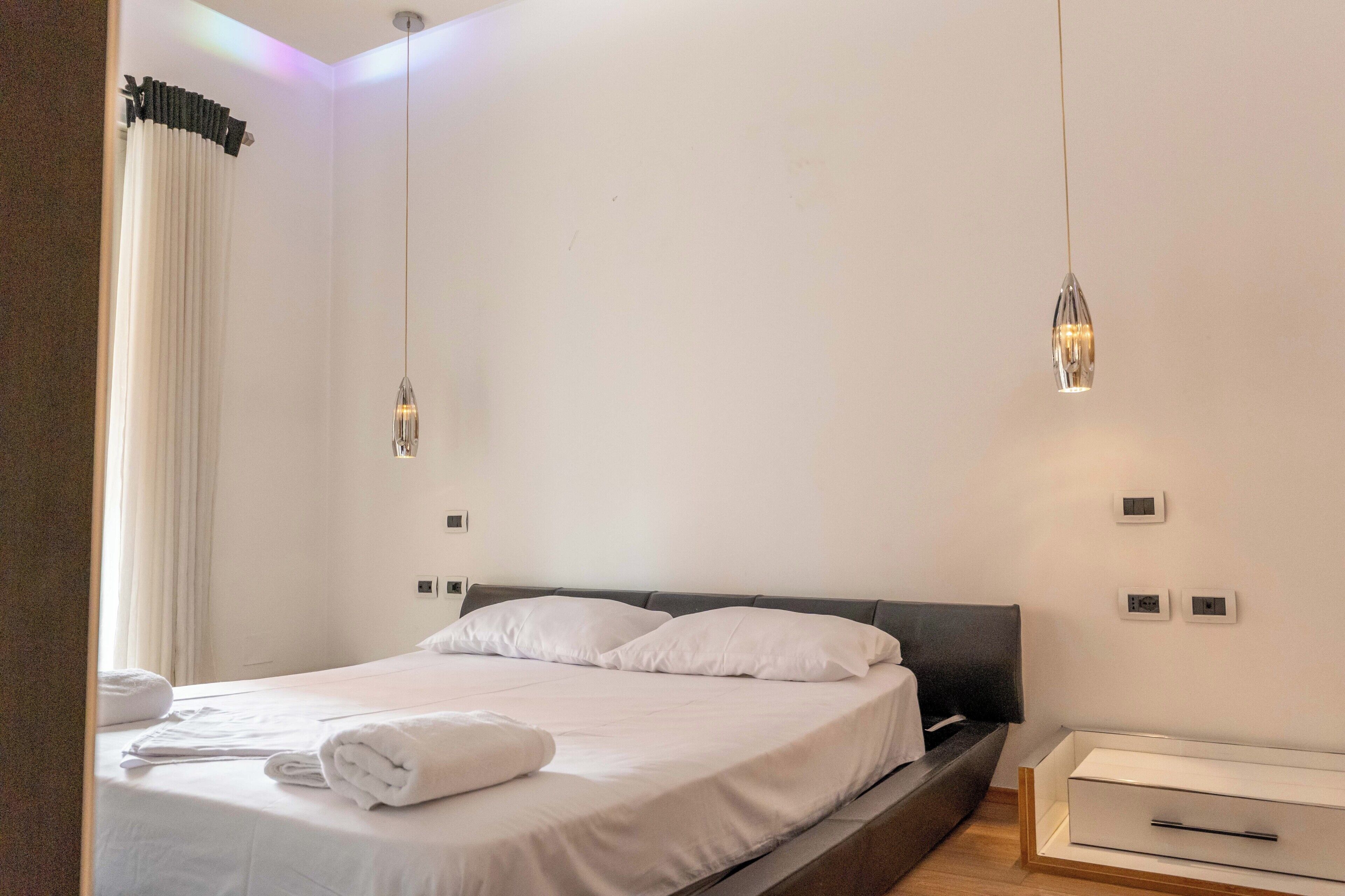 A modern hotel room with a neatly made bed, a bedside table, and a built-in bench.