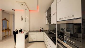 Una cocina moderna con armarios blancos, horno empotrado y una campana extractora de acero inoxidable.