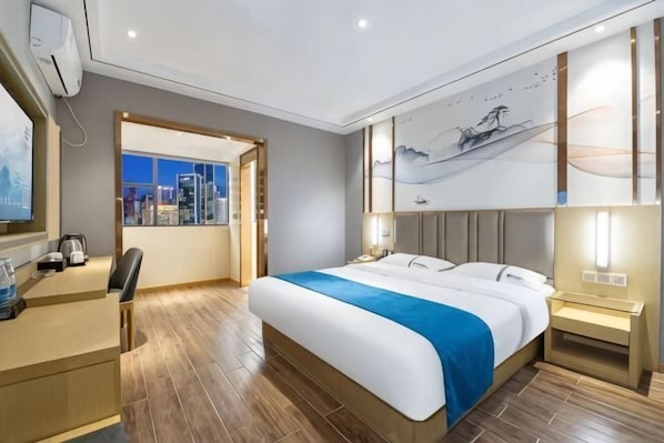 Ein Hotelzimmer mit Bett, Schreibtisch, Stuhl und Blick auf die Stadt.