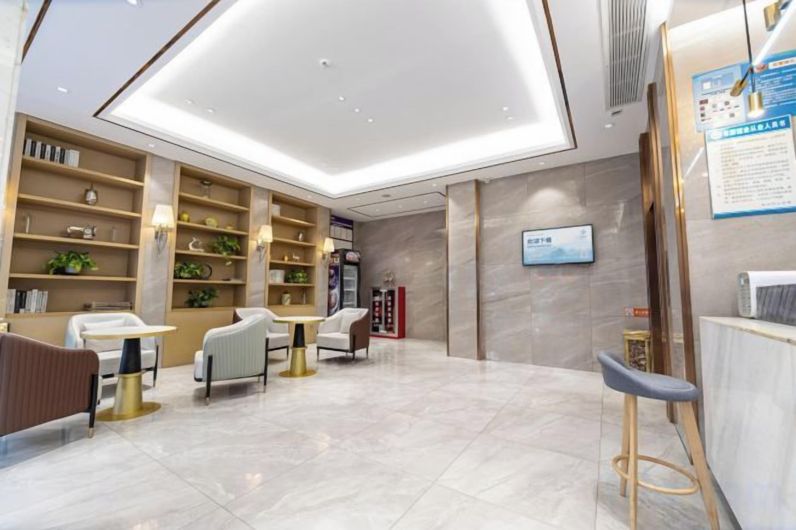 A modern hotel lobby with a reception desk, seating area, and a large open space with a high ceiling.