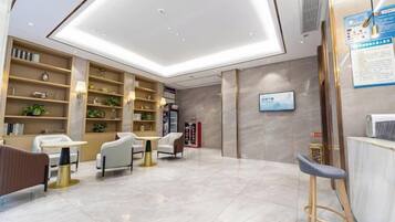 A modern hotel lobby with a reception desk, seating area, and a large open space with a high ceiling.