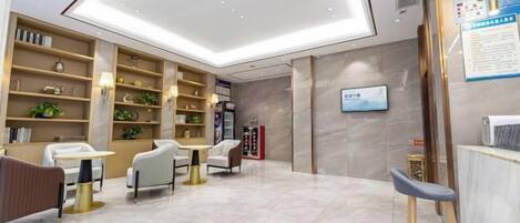 A modern hotel lobby with a reception desk, seating area, and a large open space with a high ceiling.