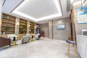 Un moderno vestíbulo de hotel con mostrador de recepción, zona de estar y un amplio espacio abierto con techo alto.