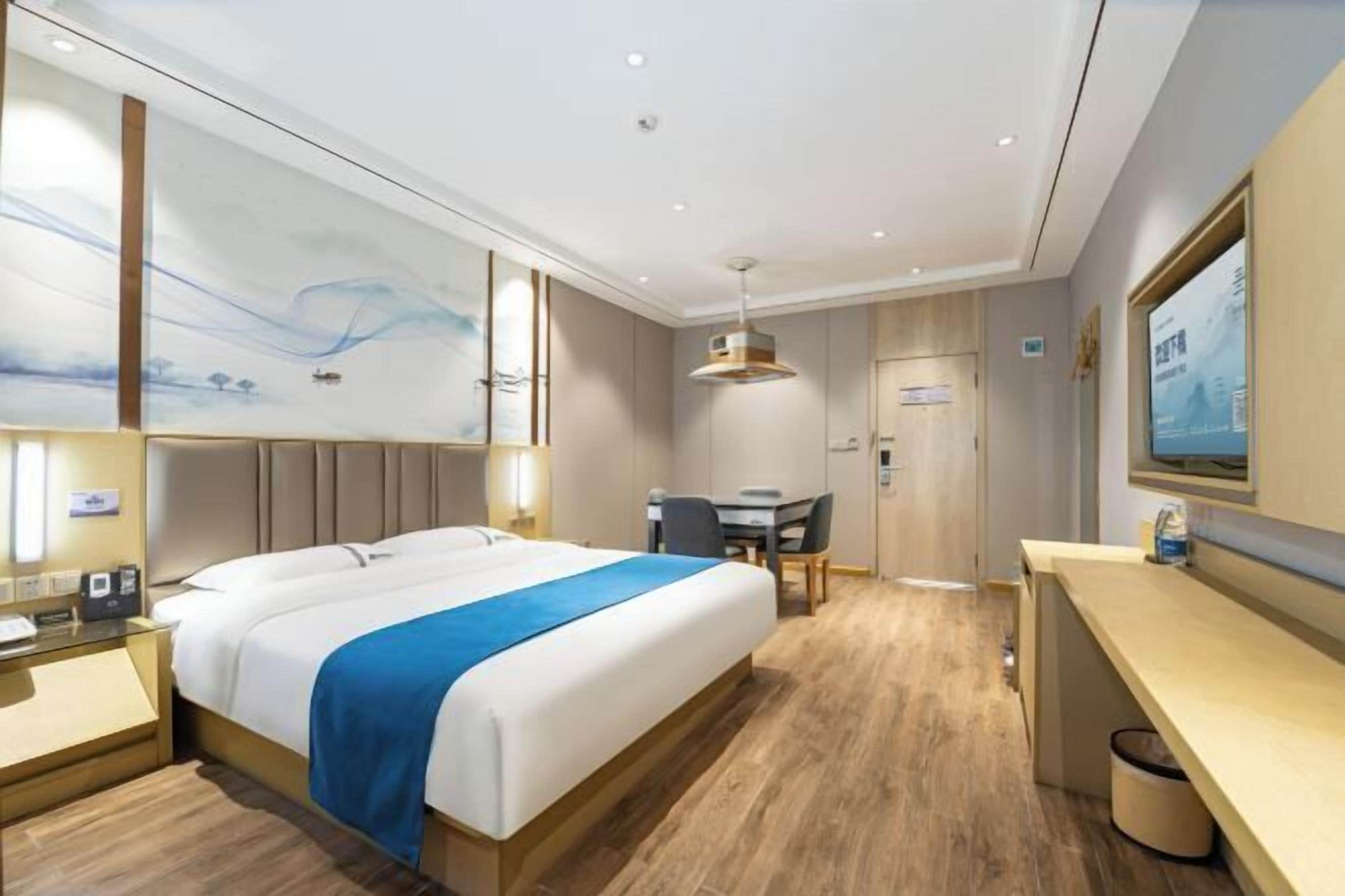 Une chambre d’hôtel avec un lit, un bureau, une chaise et une grande peinture murale.