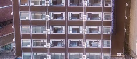 A multi-story hotel with a uniform facade, multiple balconies, and a series of air conditioning units.