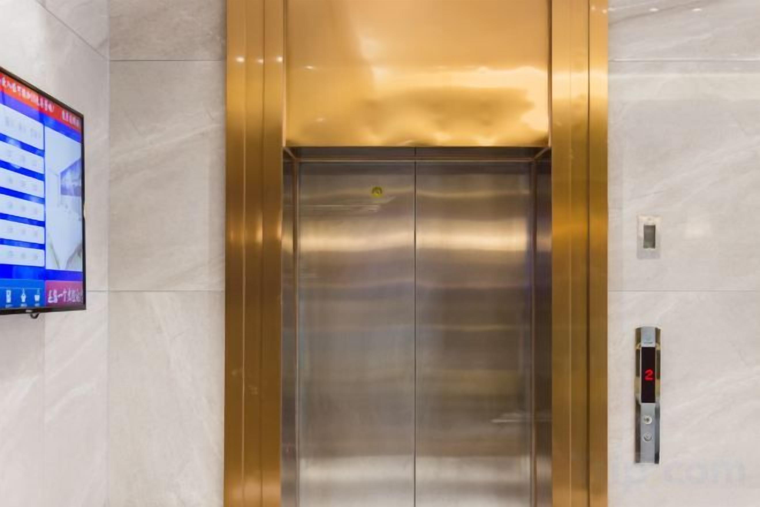 An elevator with a digital display on the wall to the left.