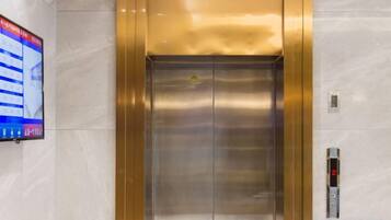 An elevator with a digital display on the wall to the left.