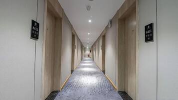 A long, narrow hotel corridor with doors on both sides, each marked with a number.