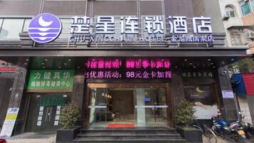 A hotel entrance with a signboard displaying amenities and a logo.