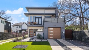 A modern two-story house with a balcony, a garage, and a well-maintained lawn. - 10-Min to ABIA, UT, Downtown Bright & Dog-Friendly w Fenced Yard 2-Car Parking (Austin)
