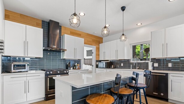 A modern kitchen with white cabinets, a central island, and pendant lighting. - 10-Min to ABIA, UT, Downtown Bright & Dog-Friendly w Fenced Yard 2-Car Parking (Austin)