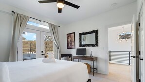 A bedroom with a bed, a desk, a computer, a mirror, and a balcony with a view. - 10-Min to ABIA, UT, Downtown Bright & Dog-Friendly w Fenced Yard 2-Car Parking (Austin)