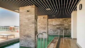 A pool area with a modern design, featuring a brick wall and metal railings.