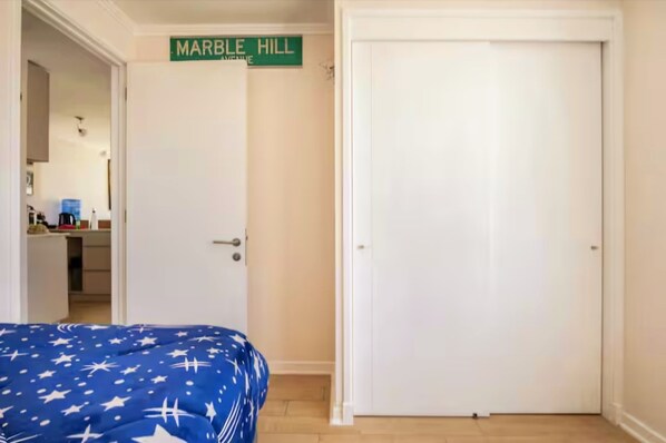 Una habitación con una cama, una puerta cerrada y un cartel sobre la puerta que dice "MARBLE HILL".
