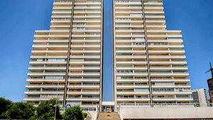 A high-rise building with multiple balconies and a clear sky.