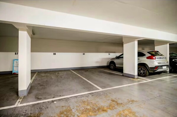 A parking garage with numbered parking spaces and a white car parked in space 86.