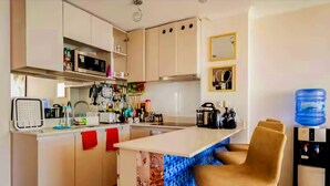 A modern kitchen with white cabinets, a central island with a blue-tiled backsplash, and a water dispenser.