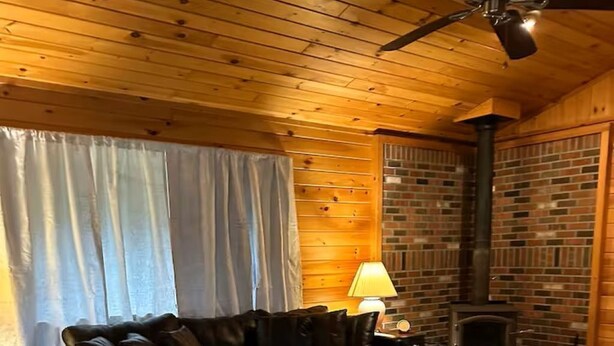A cozy living room with a leather sofa, a wooden coffee table, and a brick fireplace.
