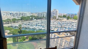 A room with a large window offering a view of a marina and cityscape.