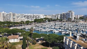 A marina with numerous boats docked, surrounded by residential buildings and greenery.
