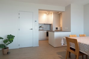 A modern kitchen with white cabinets, a central island, and a dining area with a table and chairs.