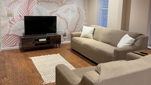 A living room with a television, sofa, and a ceiling fan. - Stylish 2-bedroom apartment with WiFi, AC in fabulous downtown French Lick (French Lick)