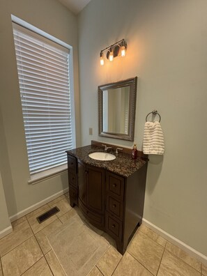 A bathroom with a granite countertop sink, a large mirror, and a towel ring.