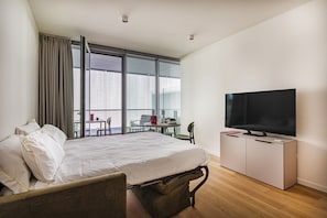 A hotel room with a bed, a TV, a desk, and a balcony.