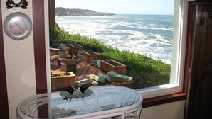 A room with a view of the ocean, a fireplace, and a clock on the wall. - Ocean Garden Suite at Whales Rendezvous (Depoe Bay)