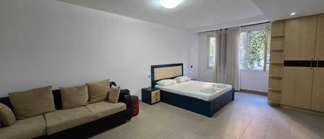 A modern bedroom with a bed, a sofa, and a wardrobe.