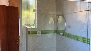 Un baño con cabina de ducha de vidrio, lavamanos y retrete.